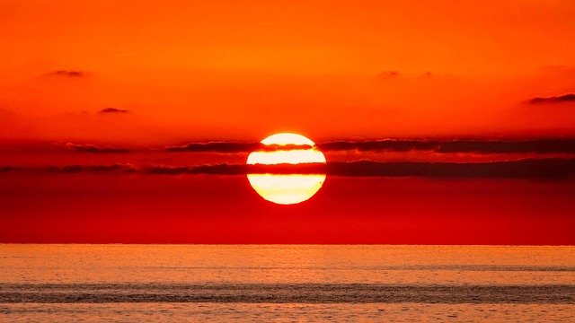 Think of the Sun as a flashlight shining through a glass of water. If the flashlight is right above the glass, the light passes straight through. But if you tilt the flashlight to the side, the light has to travel through more water. The same thing happens with the Sun and our atmosphere.